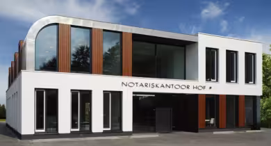 Modern kantoorgebouw met strakke architectuur en tekst notariskantoor hof boven de ingang, blauwe lucht op de achtergrond